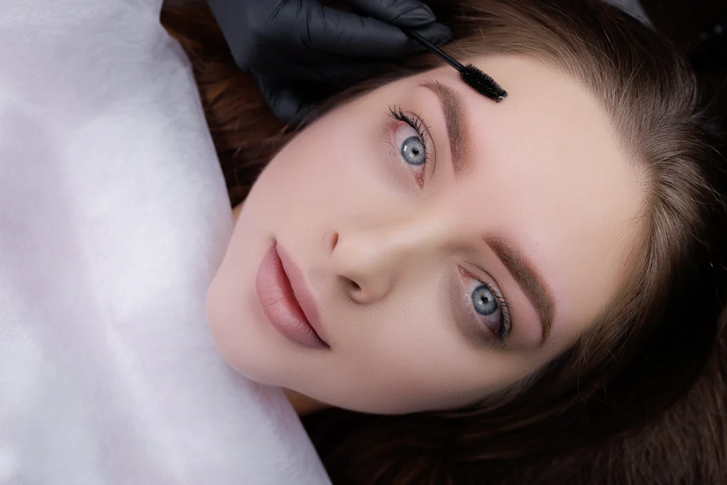 Esteticista peinando cejas de clienta